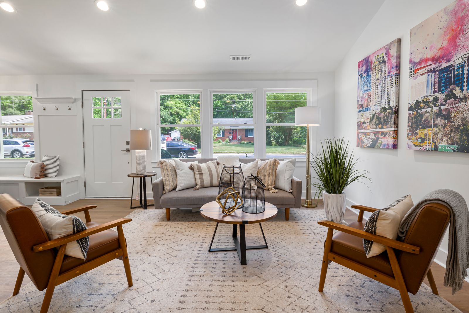 Bright living room with a sofa, wood chairs, and large windows