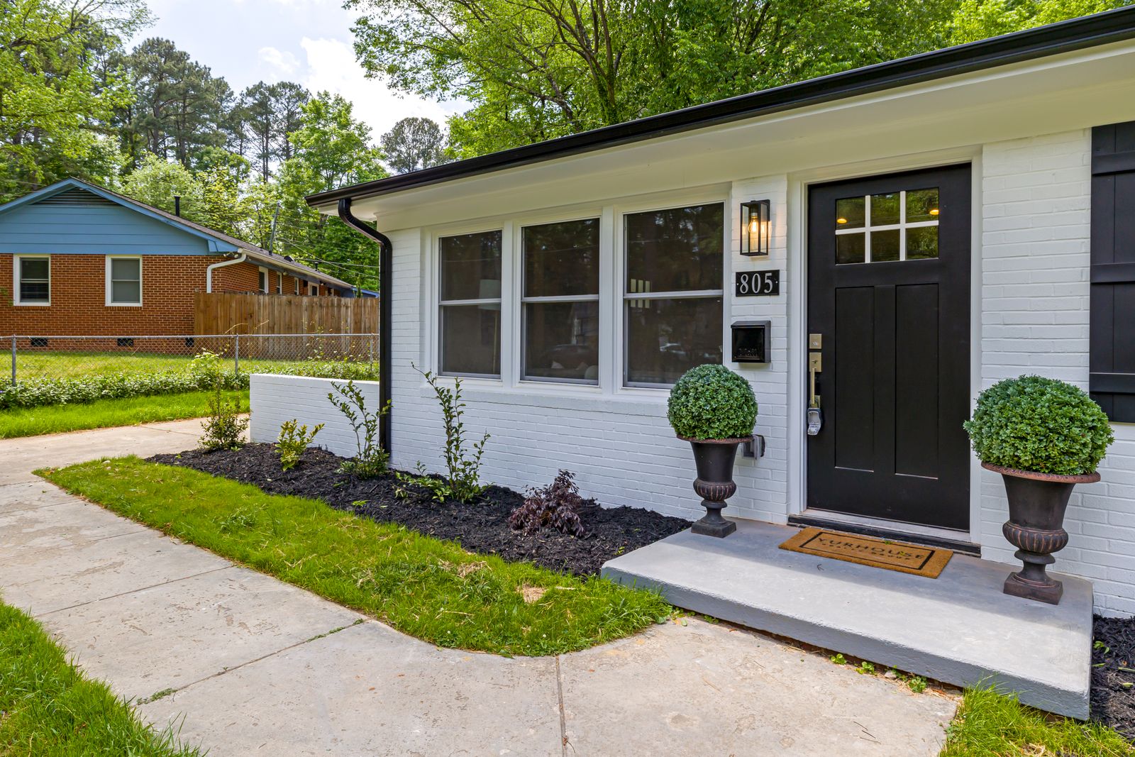 White brick home with a black front door and two planters